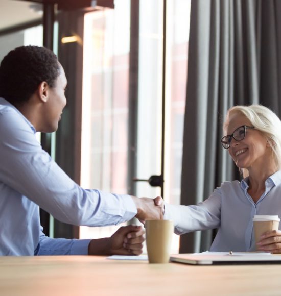 Smiling middle-aged Caucasian businesswoman handshake african American business partner or client get acquainted at meeting, diverse colleagues shake hands closing deal in office. Partnership concept